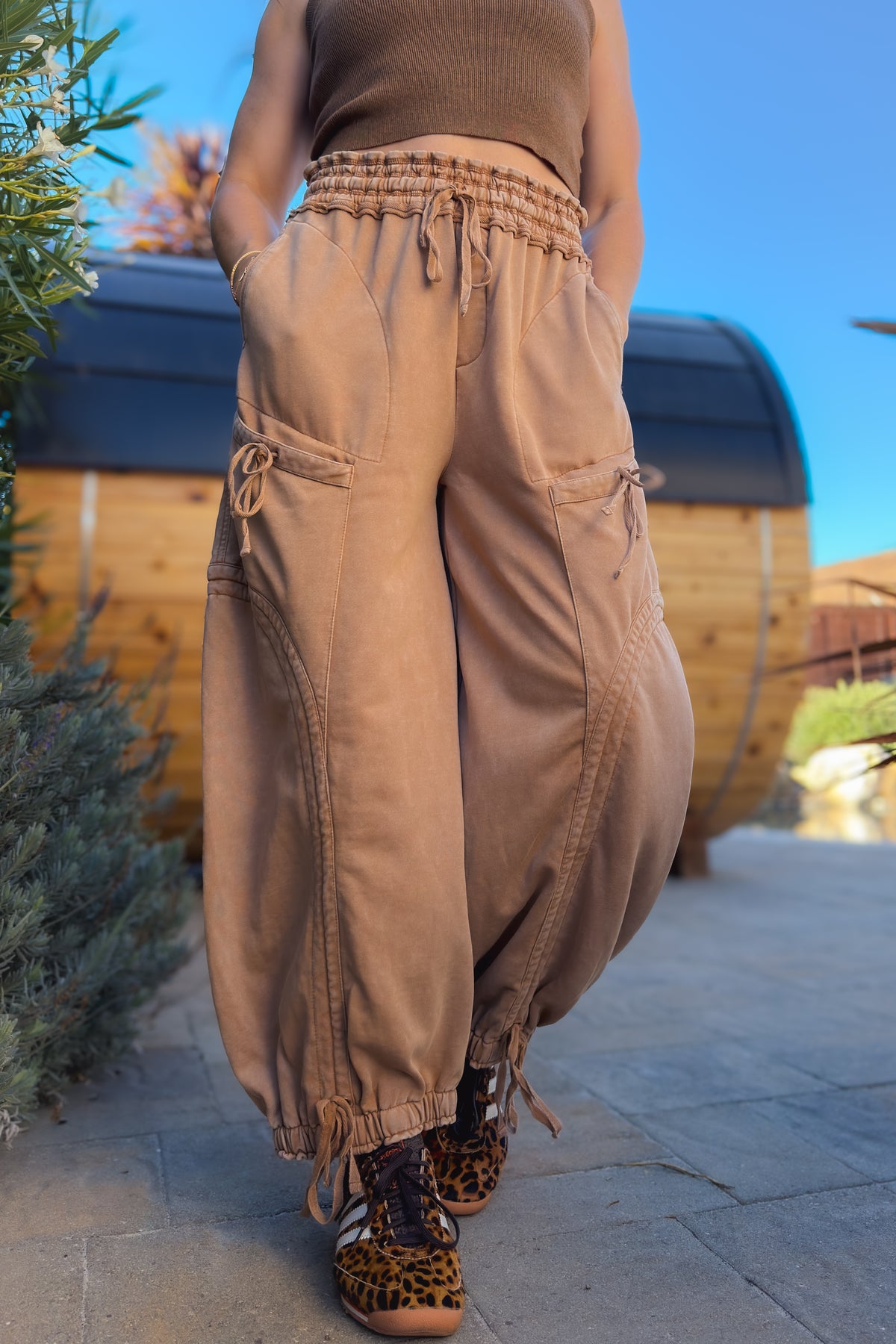 Side view of tan cargo pants showing oversized utility pocket and curved leg seam detailing