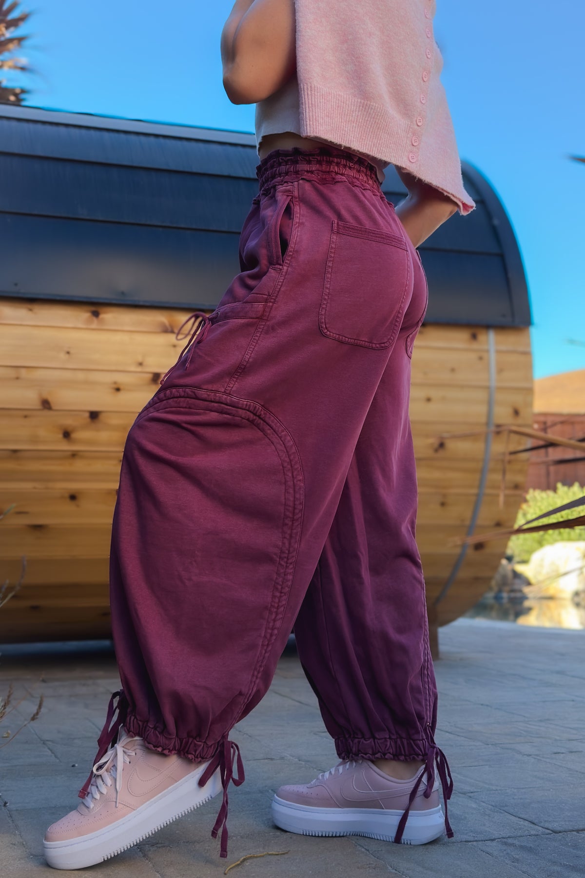 Women’s burgundy cargo pants with relaxed wide leg fit, elastic waistband and adjustable ankle ties