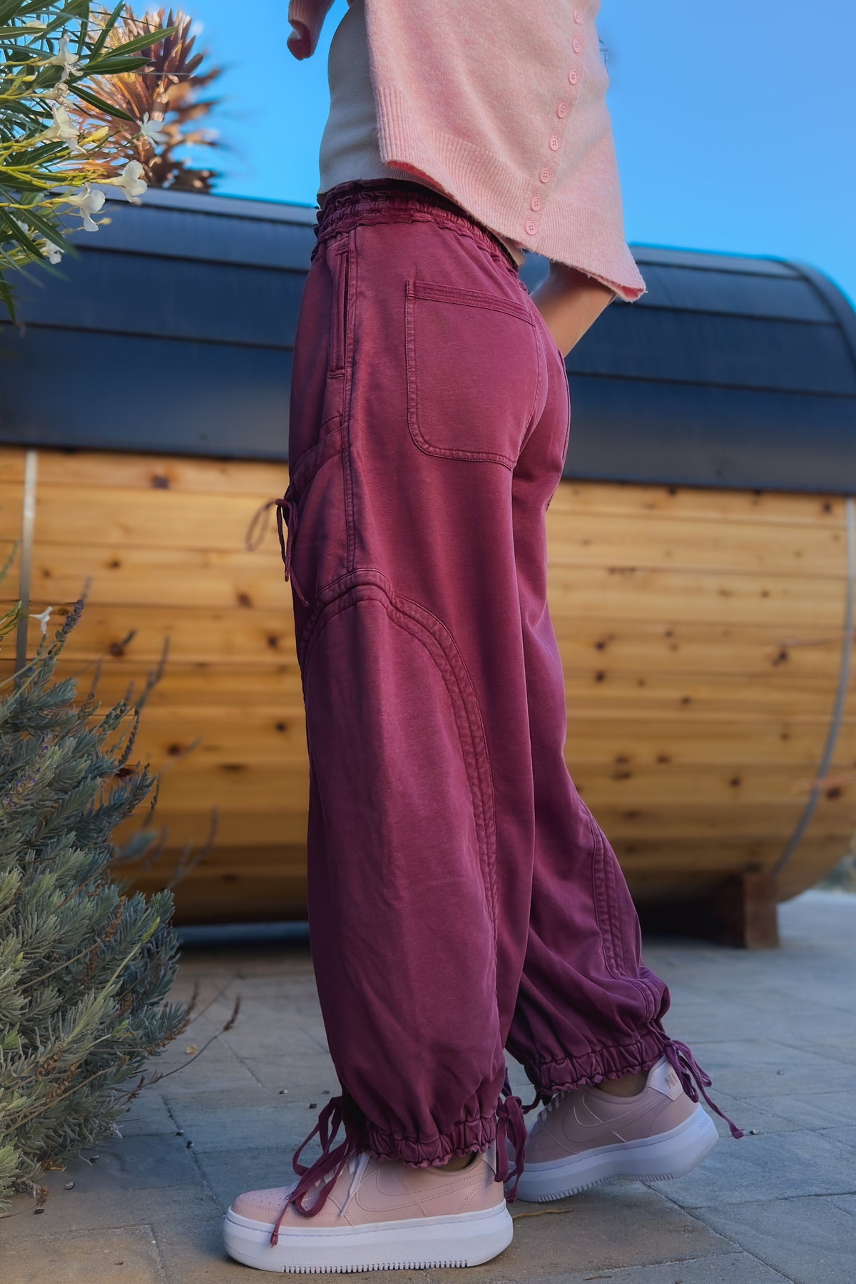 Side view of varsity burgundy cargo pants showing curved seam details and balloon-style leg