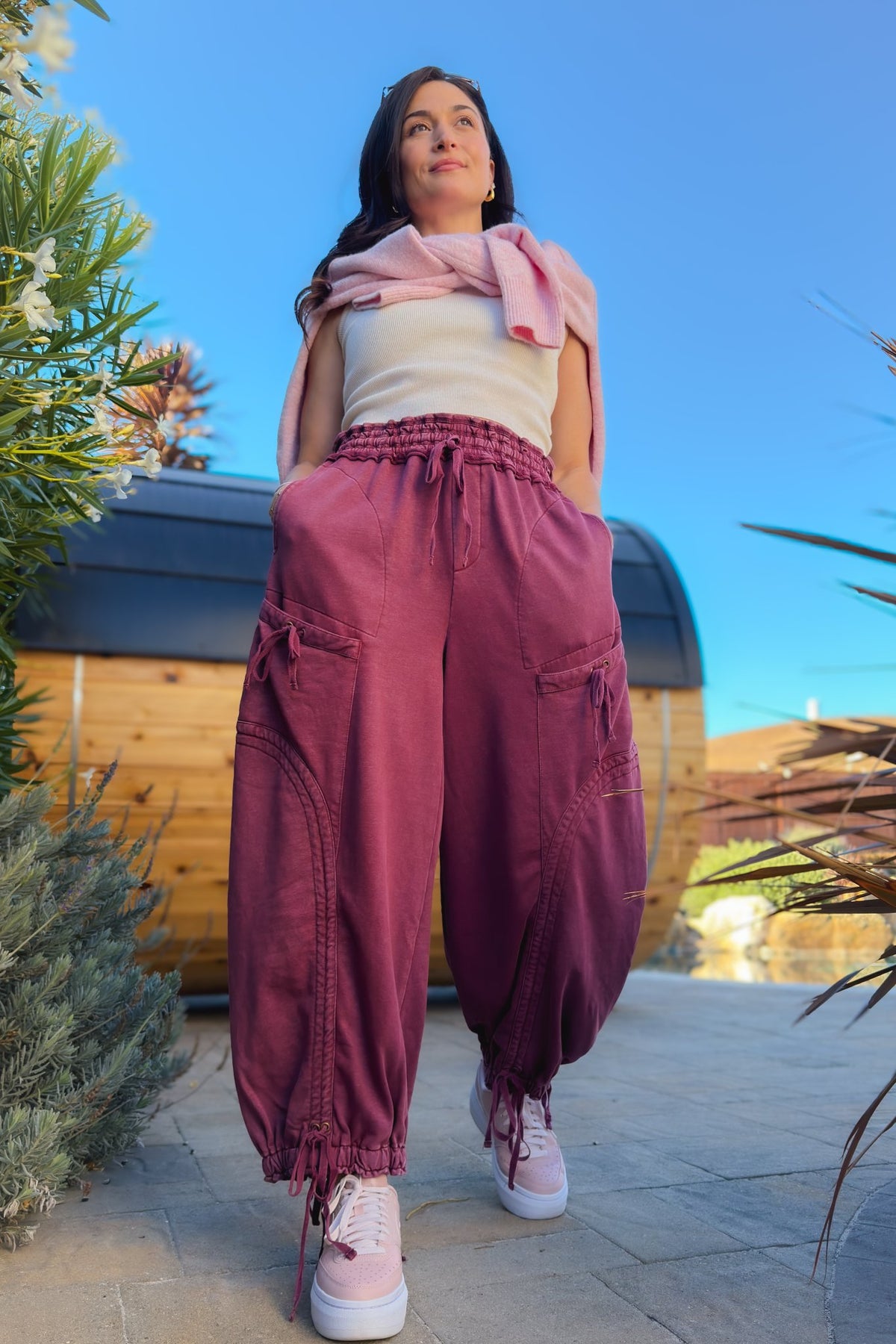 Varsity burgundy wide leg cargo pants styled with cream top, pink sweater and sneakers