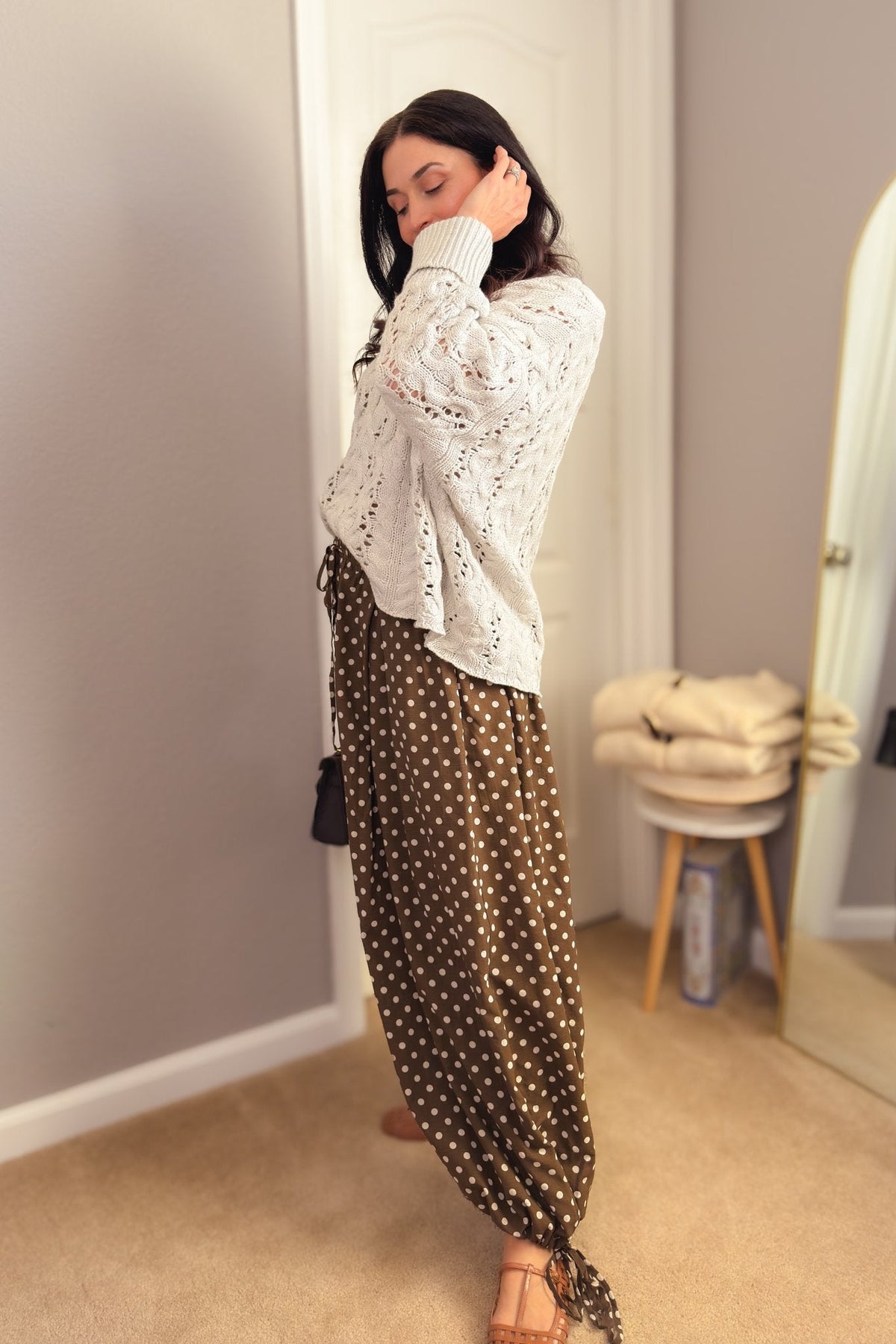 Brown polka dot balloon pants styled with a cream cable knit sweater, brown woven flats and a mini handbag for fall.