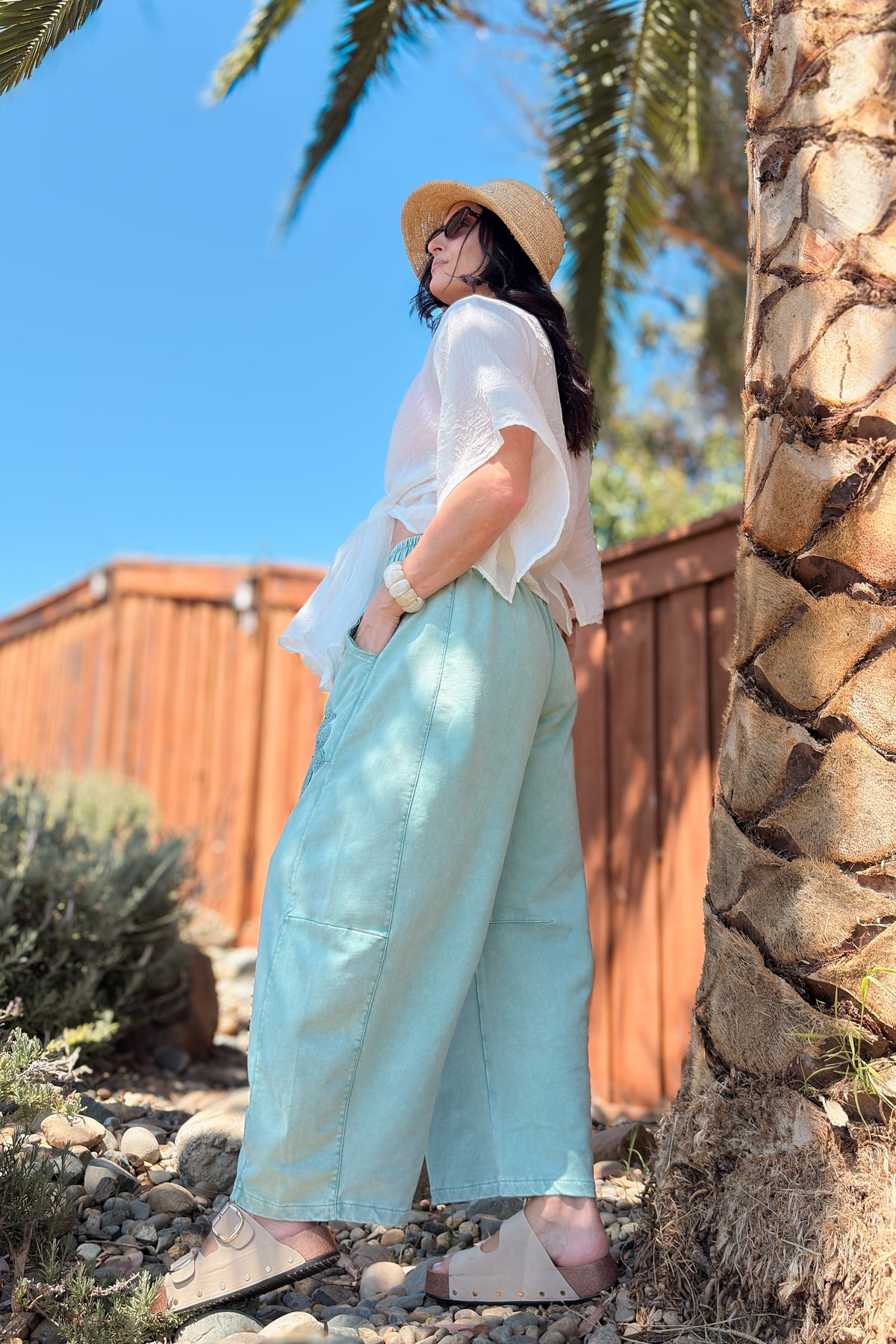 Side view of green mineral wash crochet barrel leg pants showing the relaxed silhouette and curved barrel leg shape.