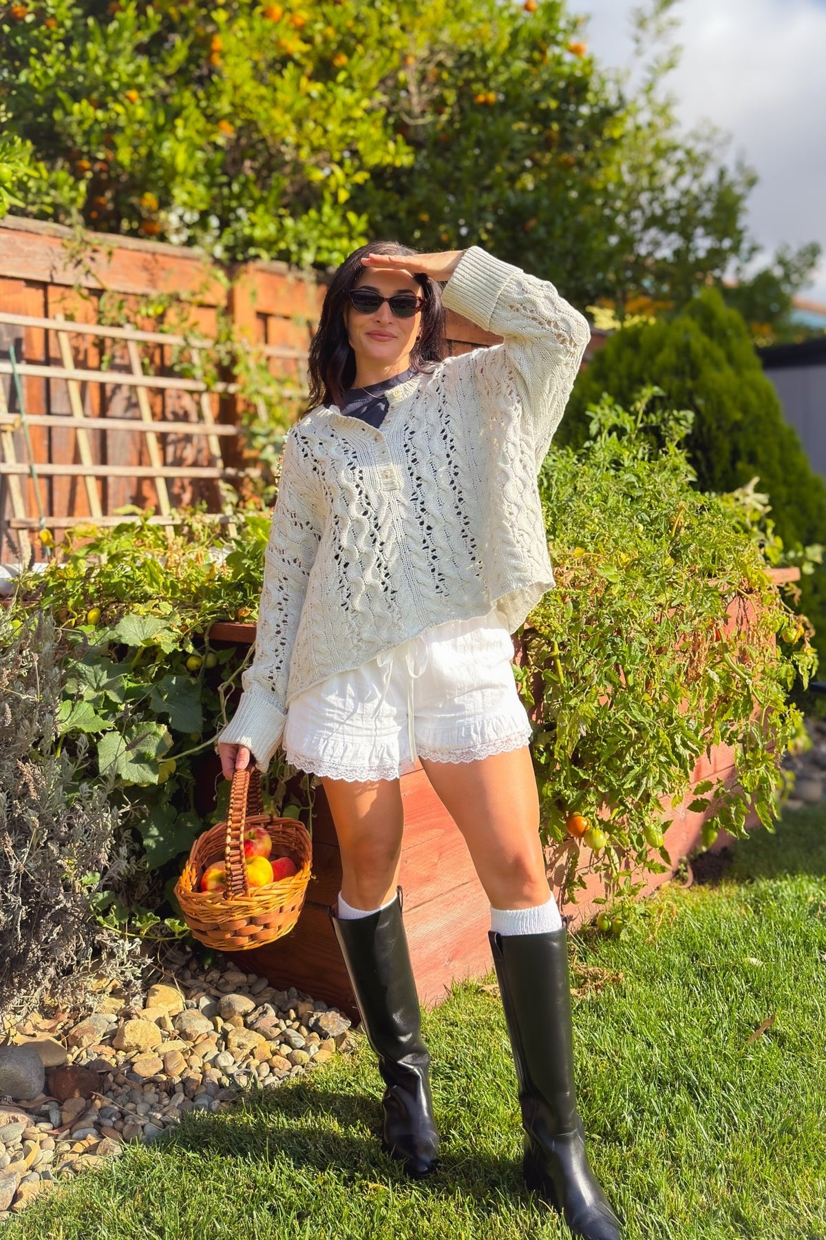 Oversized light gray cable knit sweater styled in a feminine fall outfit with tall riding boots.