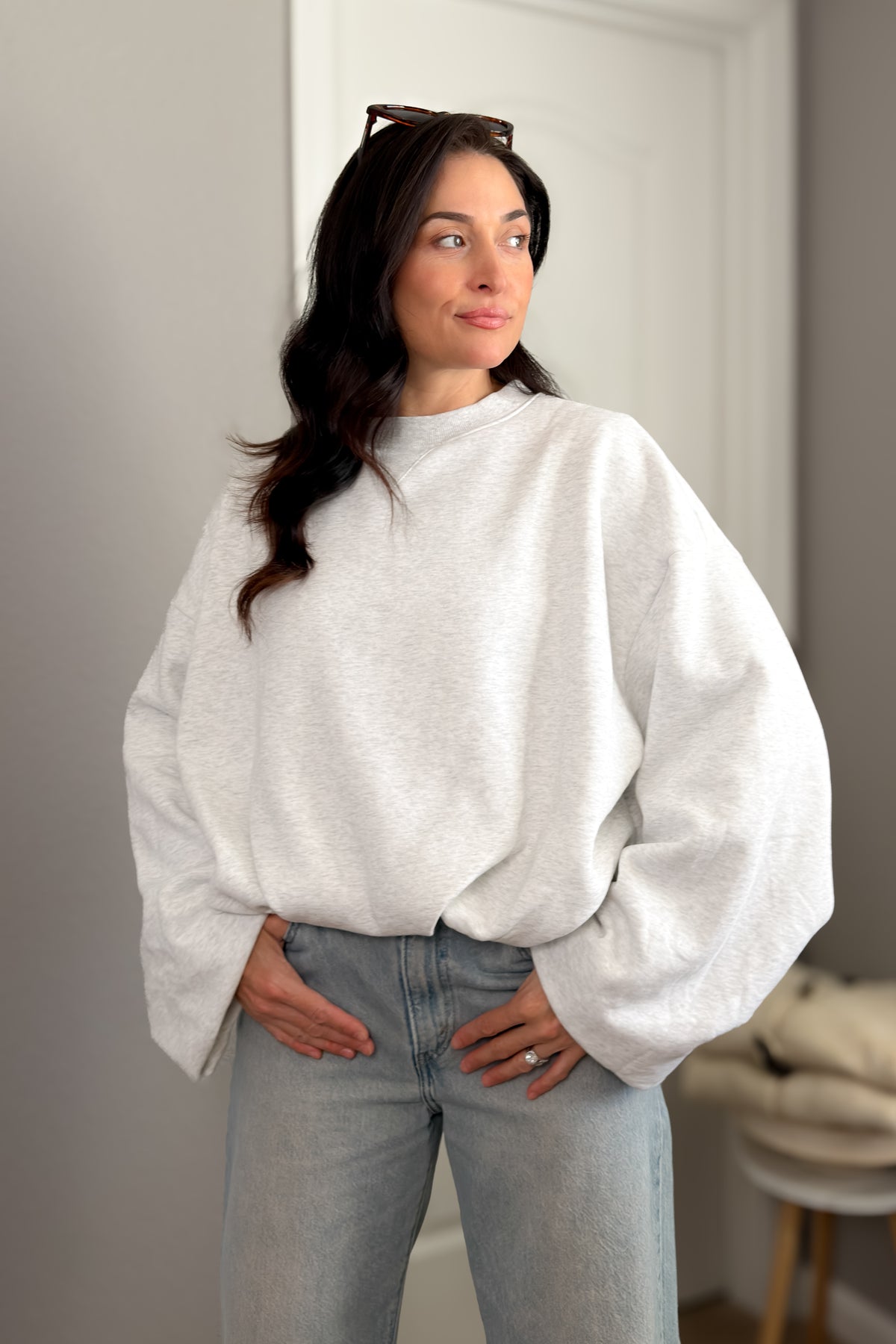 Women’s light heather gray oversized crewneck sweatshirt with relaxed boxy fit and wide sleeves styled with light wash jeans.