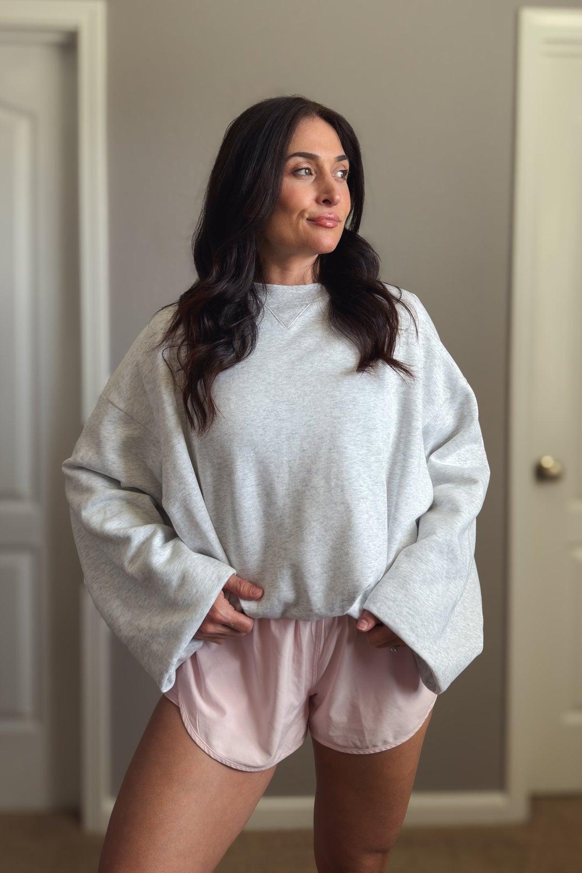 Close-up of light heather gray oversized sweatshirt showing the soft knit texture, crew neckline and relaxed sleeve design.