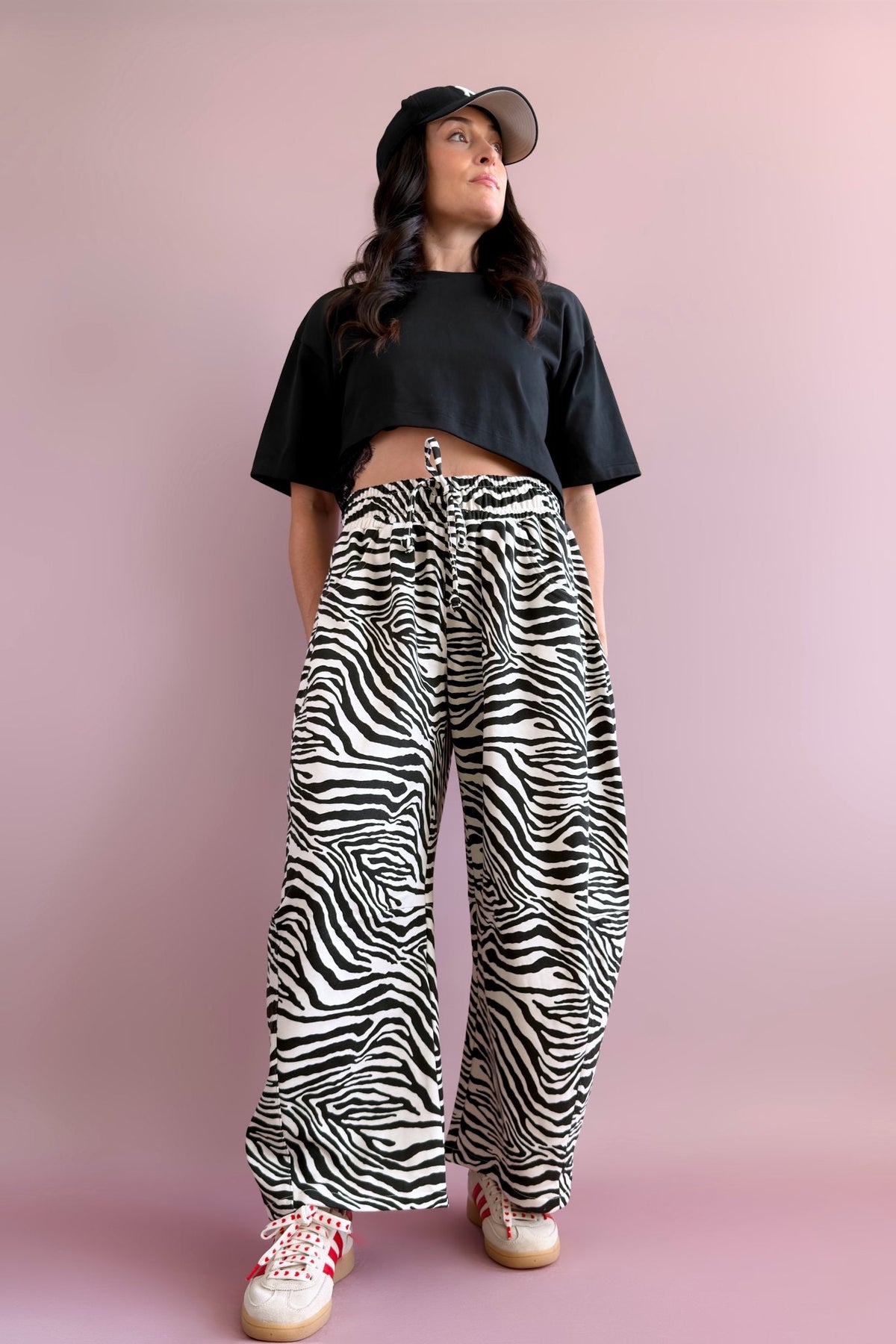 Women’s black and ivory zebra statement pants styled with a black cropped tee and baseball cap